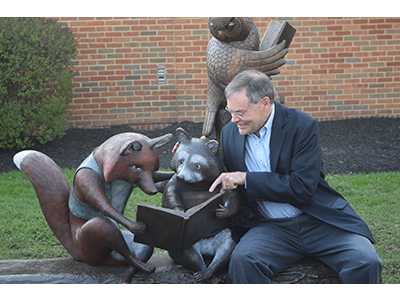 Mike posing with Reading With Friends Statue